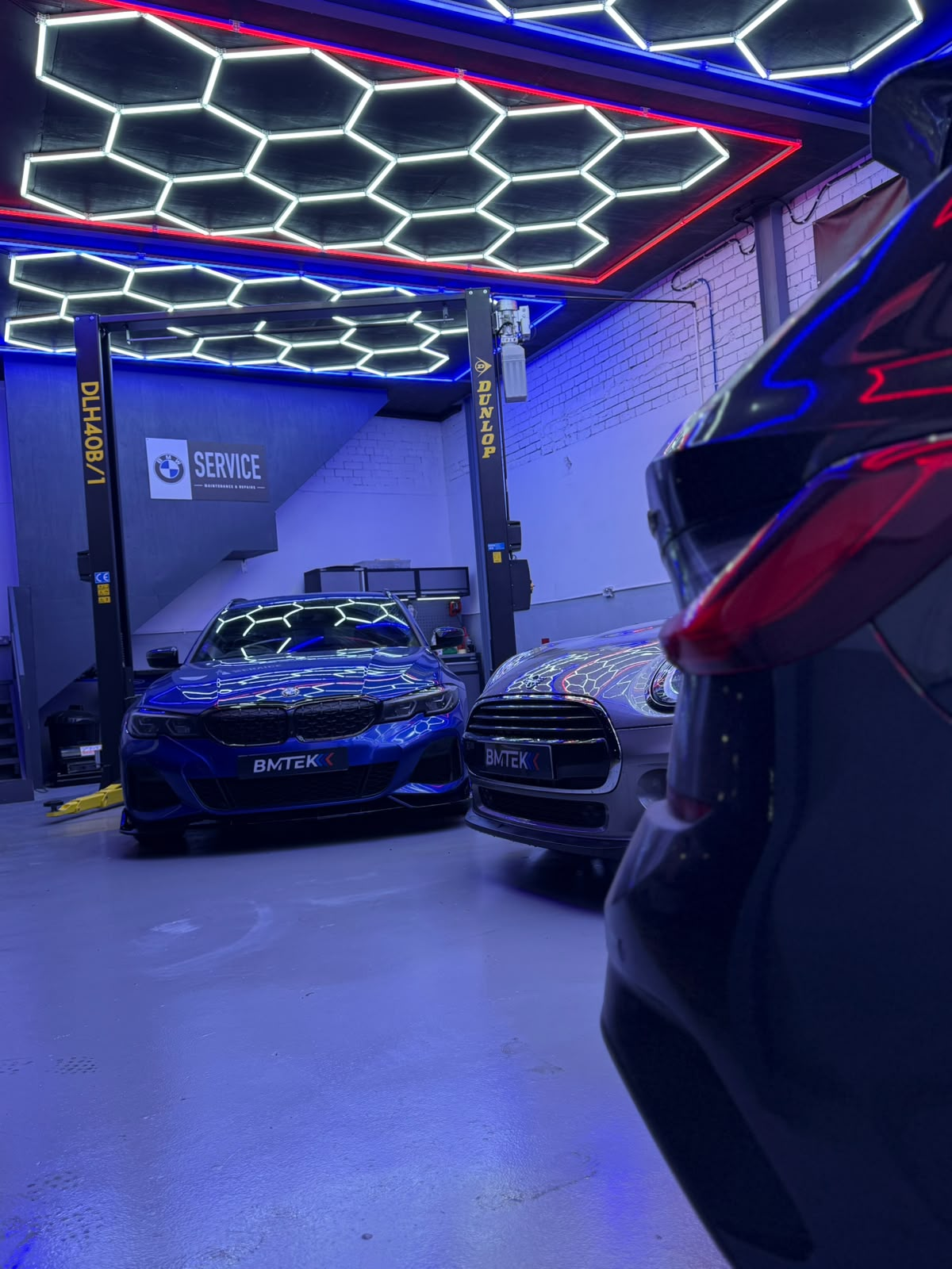 BMW and MINI parked inside the BMTEK workshop under hexagon lighting